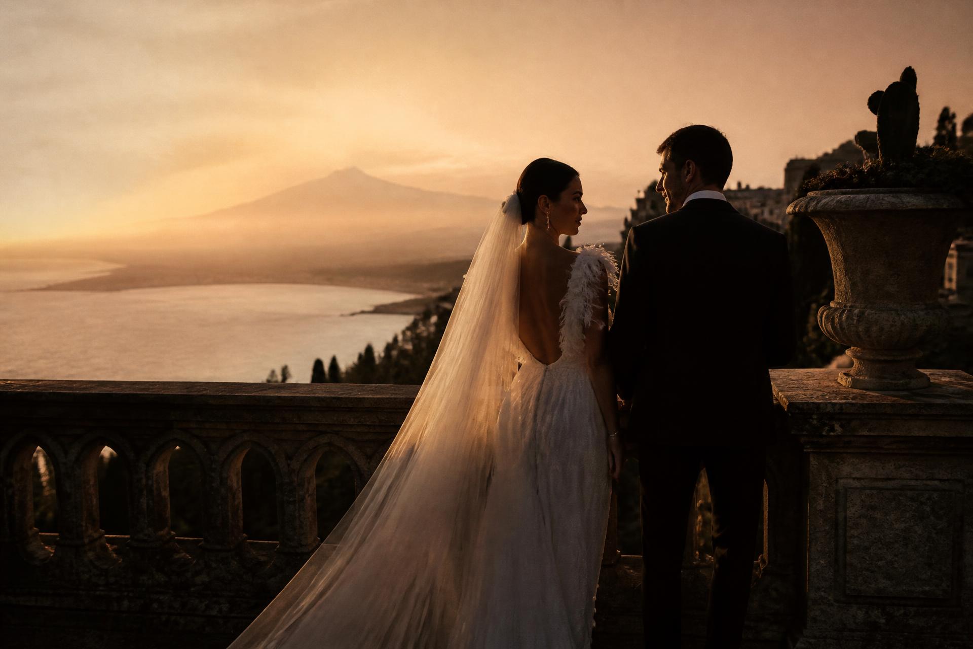 Bride and groom on a terrace in Sicily at sunset with the sea behind them